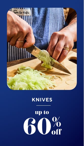 Knives up to 60% off. Chefs knife slicing leeks on wooden board.