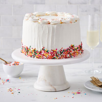 white birthday cake with rainbow colored sprinkles