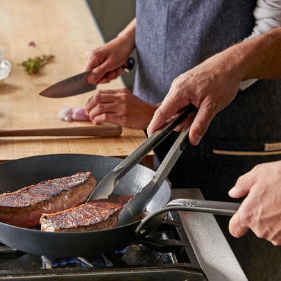 chefs searing steaks in skillet