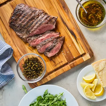 Steak Tagliata on cutting board with Arugula and Parmesan