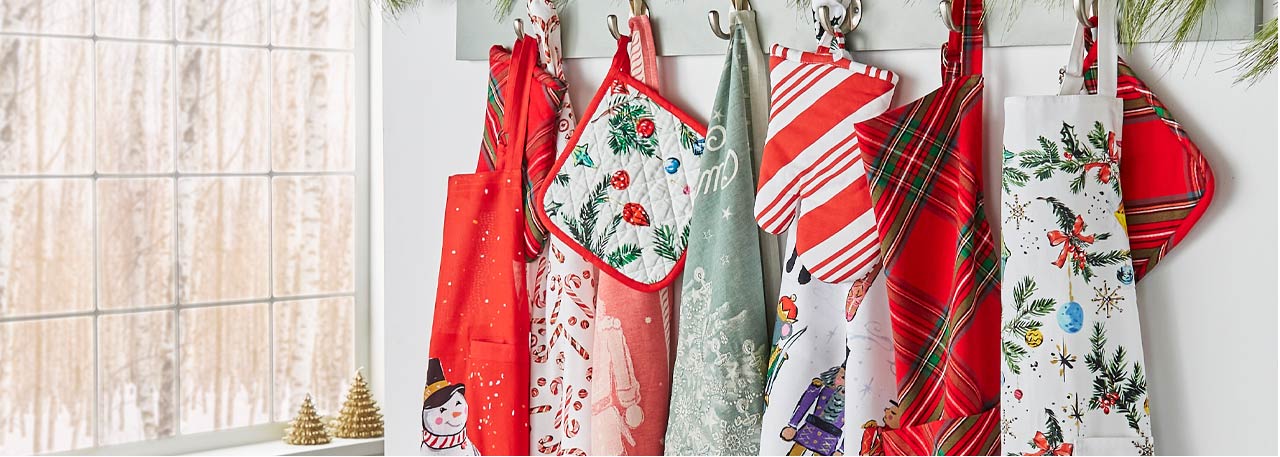 Holiday aprons, towels and oven mitts hanging on hooks