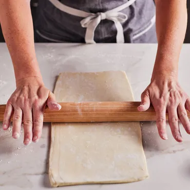Person rolling out Homemade Laminated Dough on marble counter