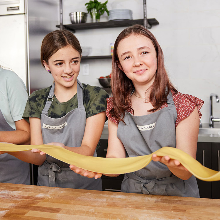 two teen girls making fresh pasta sheets