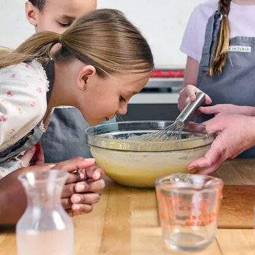 kids in Sur La Table kitchen with cake batter in bowl