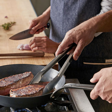 chef searing steaks in skillet