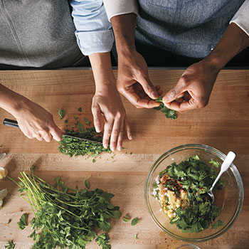 Two chefs chopping herbs