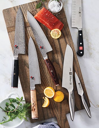 Chef's knives on cutting board with salmon and lemons