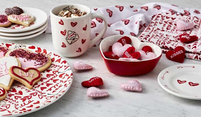 white plates, mugs and linens with red and pink heart motif