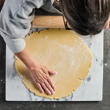 Person rolling out pastry dough on a marble surface