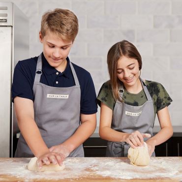 teen girl and boy kneading dough in kitchen
