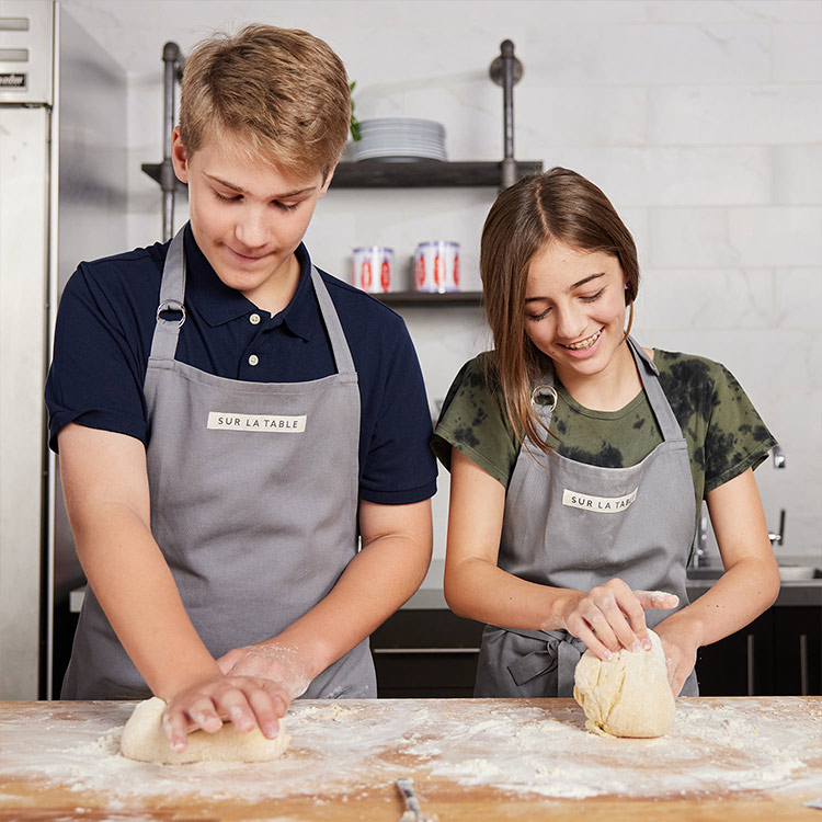 Teen girl and boy kneading bread dough