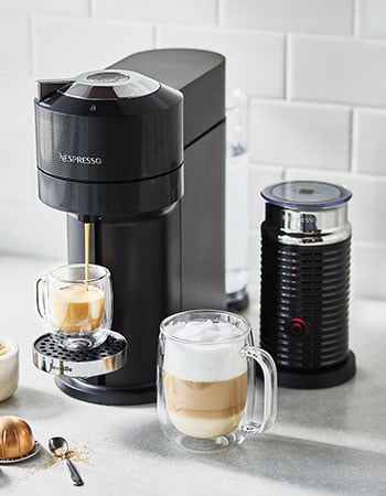 Nespresso coffee maker brewing espresso with milk frother on the side