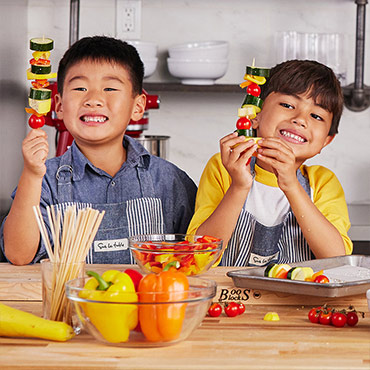 two boys making vegetable skewers