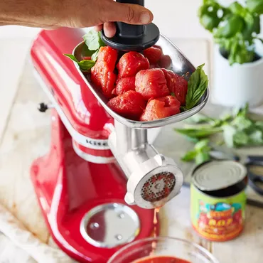 tomatoes being crushed in KitchenAid food grinder attachment