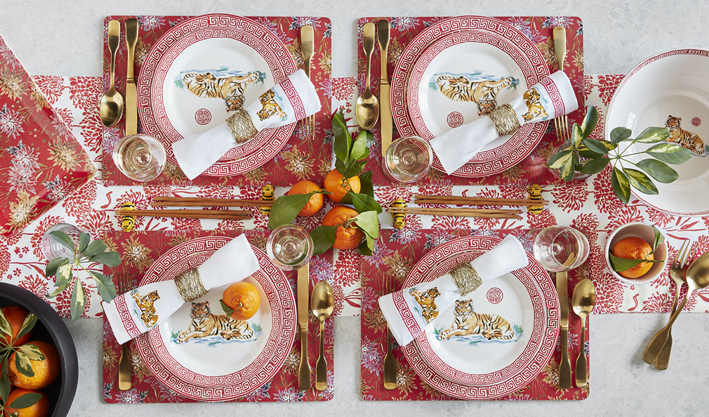 Tiger dinnerware and napkins, with gold flatware and bowl of oranges