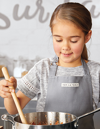 girl stirring pot of tomato sauce