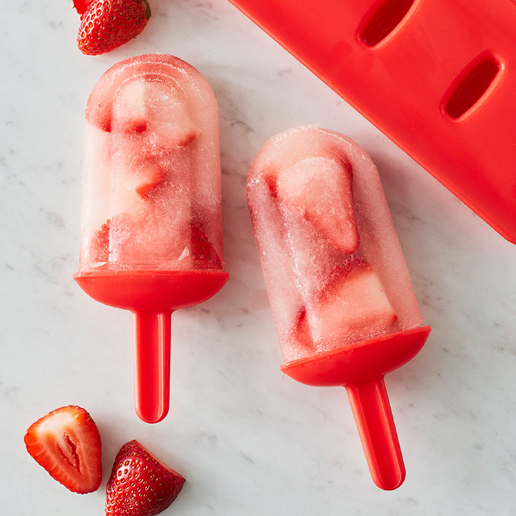 Red ice pop molds with fresh strawberries