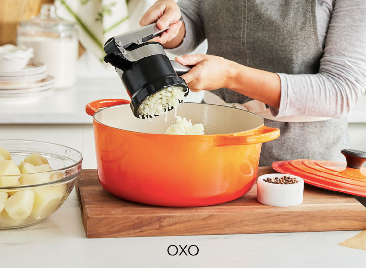 OXO potato ricer ricing potatoes into orange pot
