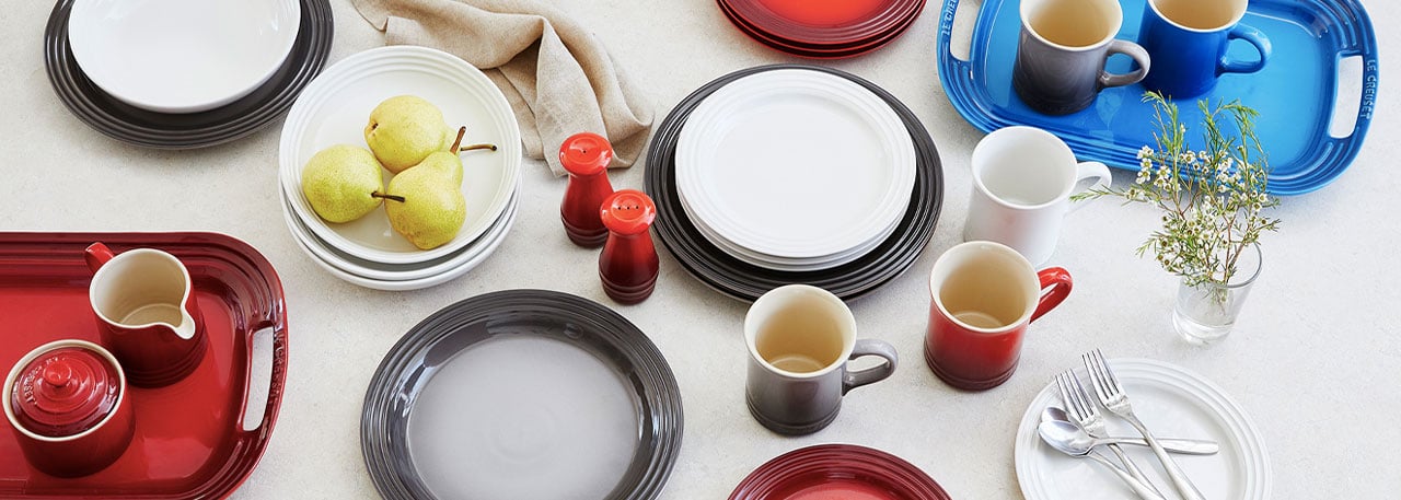 Le Creuset dinner plates, platters and mugs in red, gray and white colors